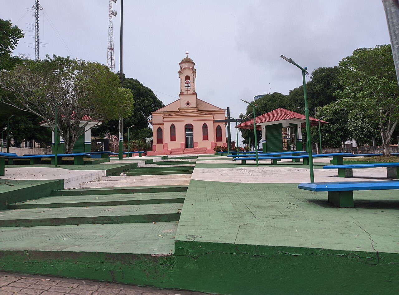 Praça e igreja no centro de Manacapuru, com torres de comunicação ao fundo